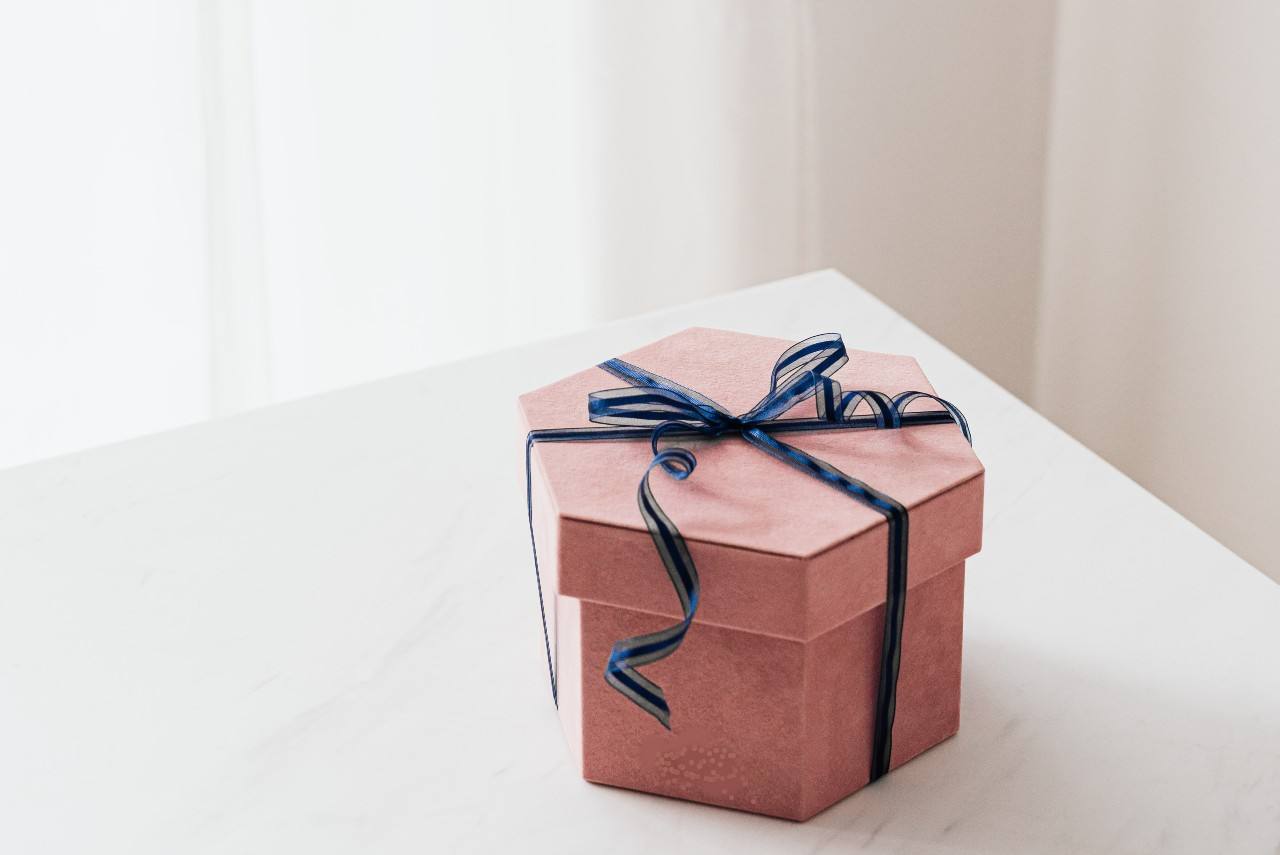 pink hexagonal gift box wrapped in blue ribbon
