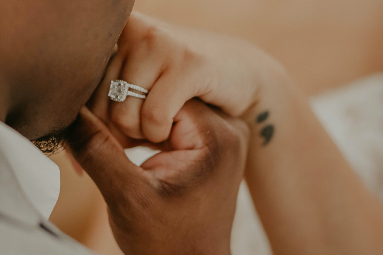 a man kissing a woman’s hand wearing a platinum engagement ring