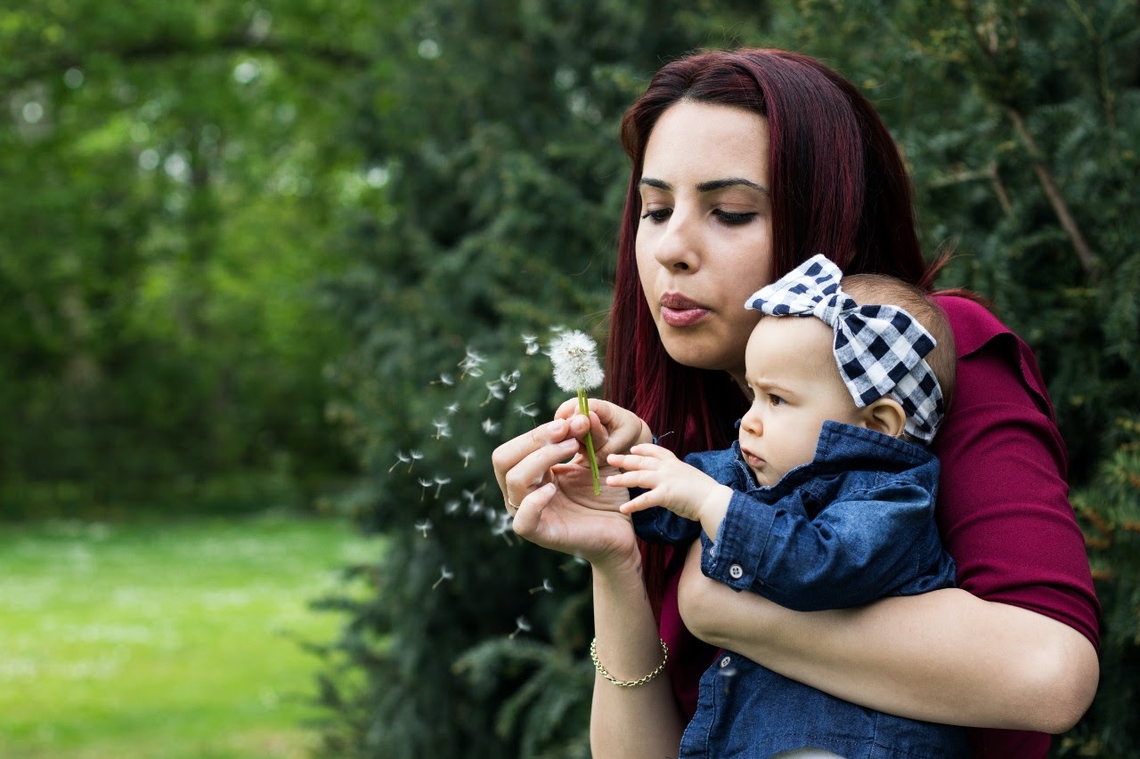 woman blowing on dandelion