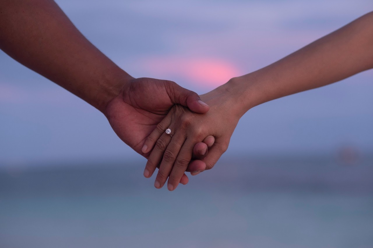 couple with engagement ring holding rings