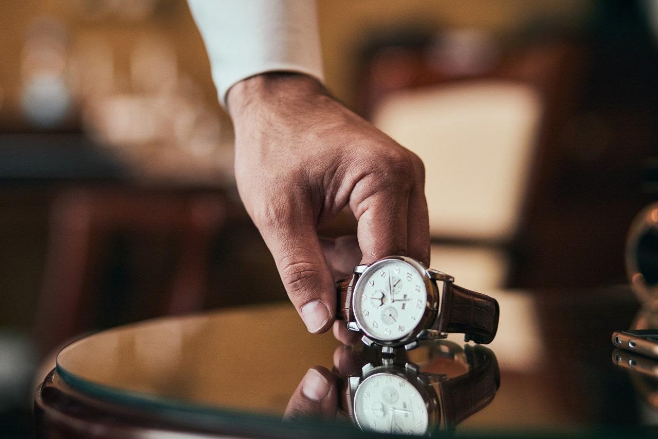 A person putting down a luxury watch with an alligator leather band
