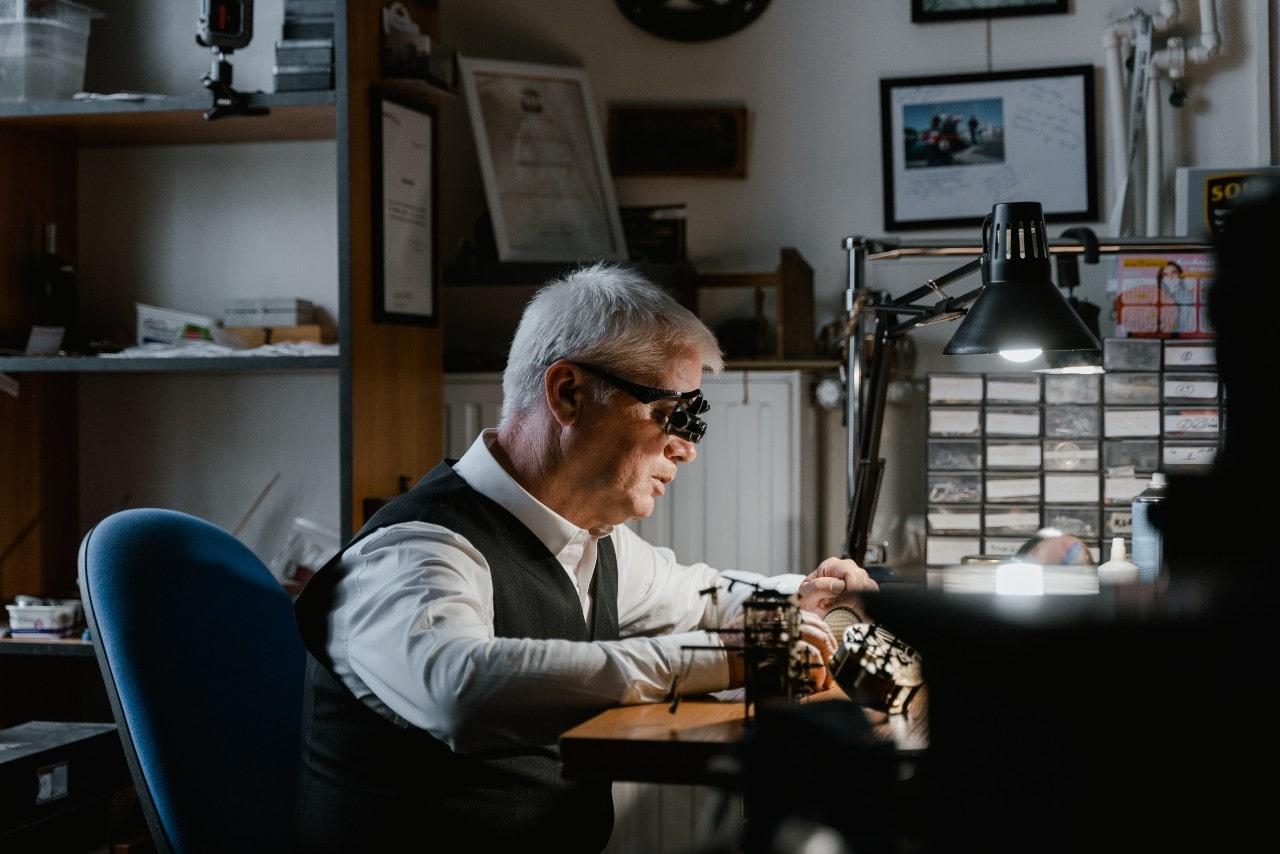 Watchmaker working diligently at their work bench on a timepiece