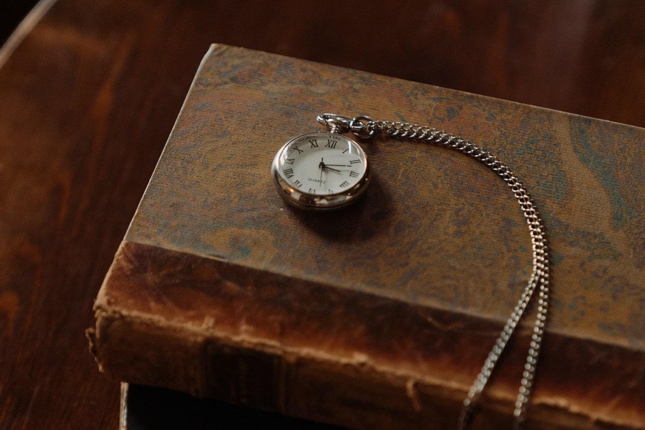 A pocket watch sitting on top of an old book