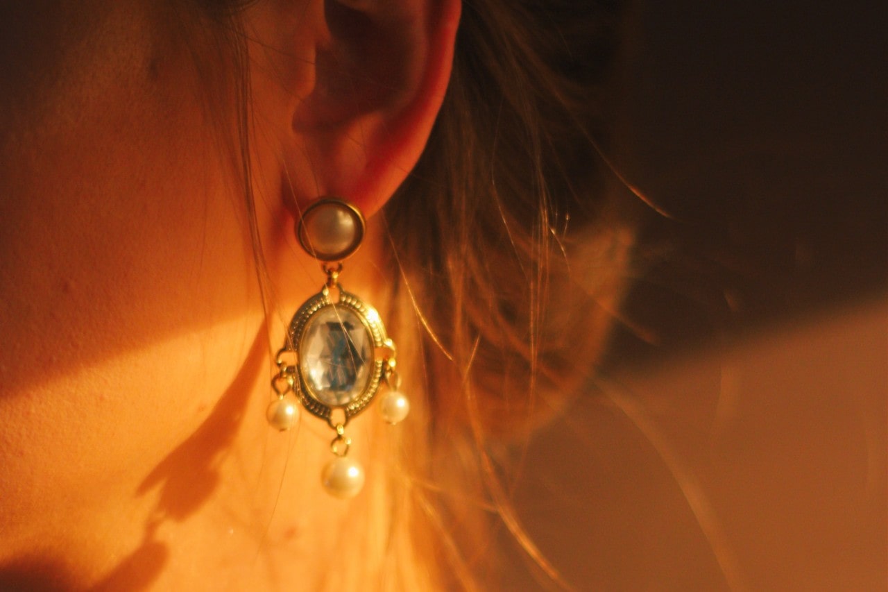 Pearl and quartz drop earrings with an intricate design while the person’s hair is swept up