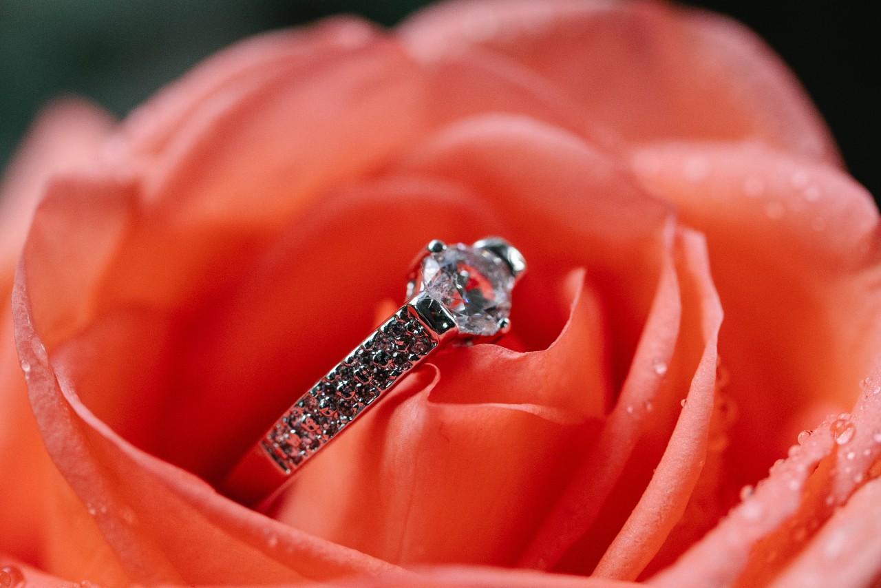 A sidestone engagement ring sitting inside an orange rose