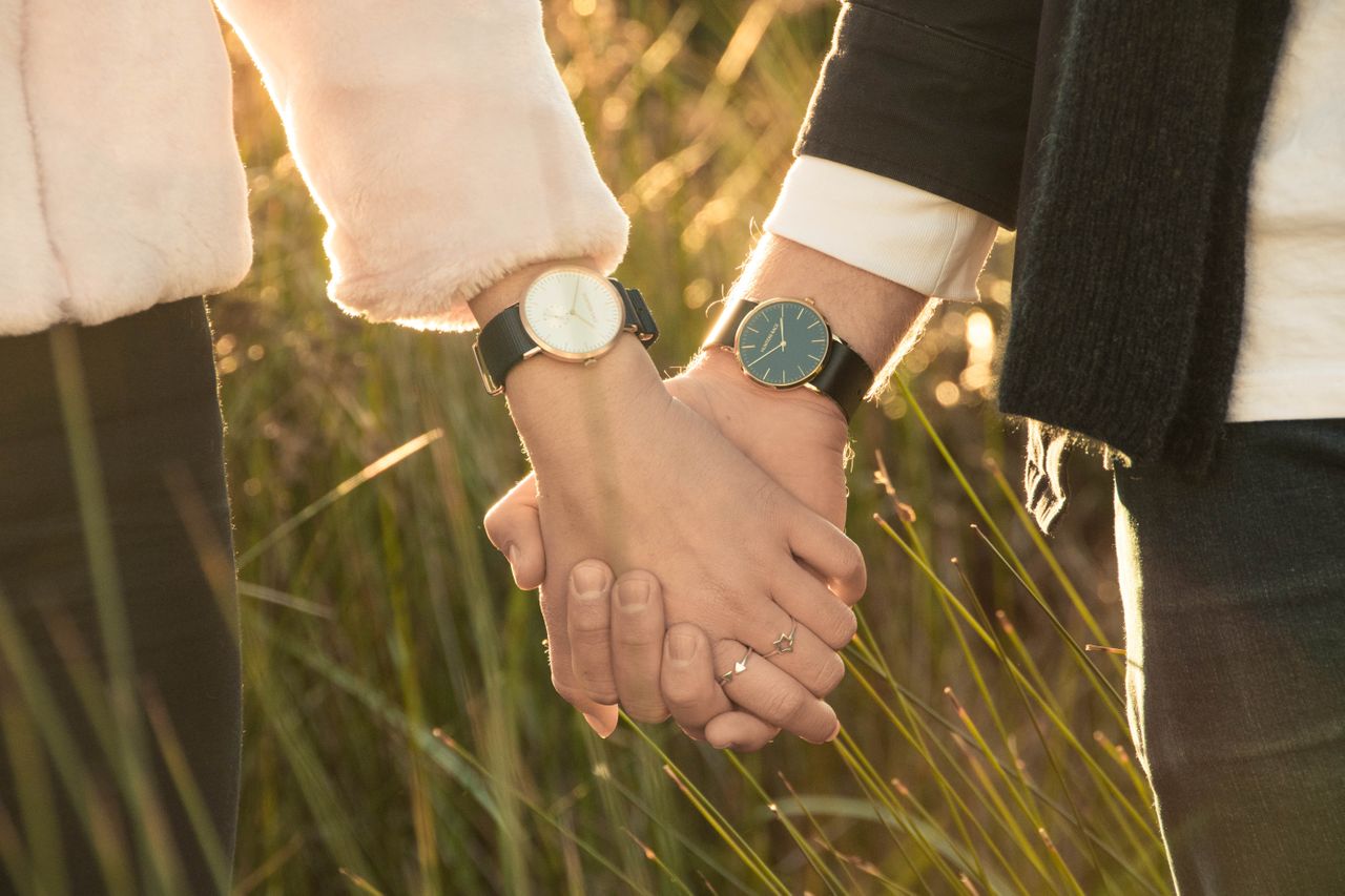 A couple holding hands wearing similar minimalist watches