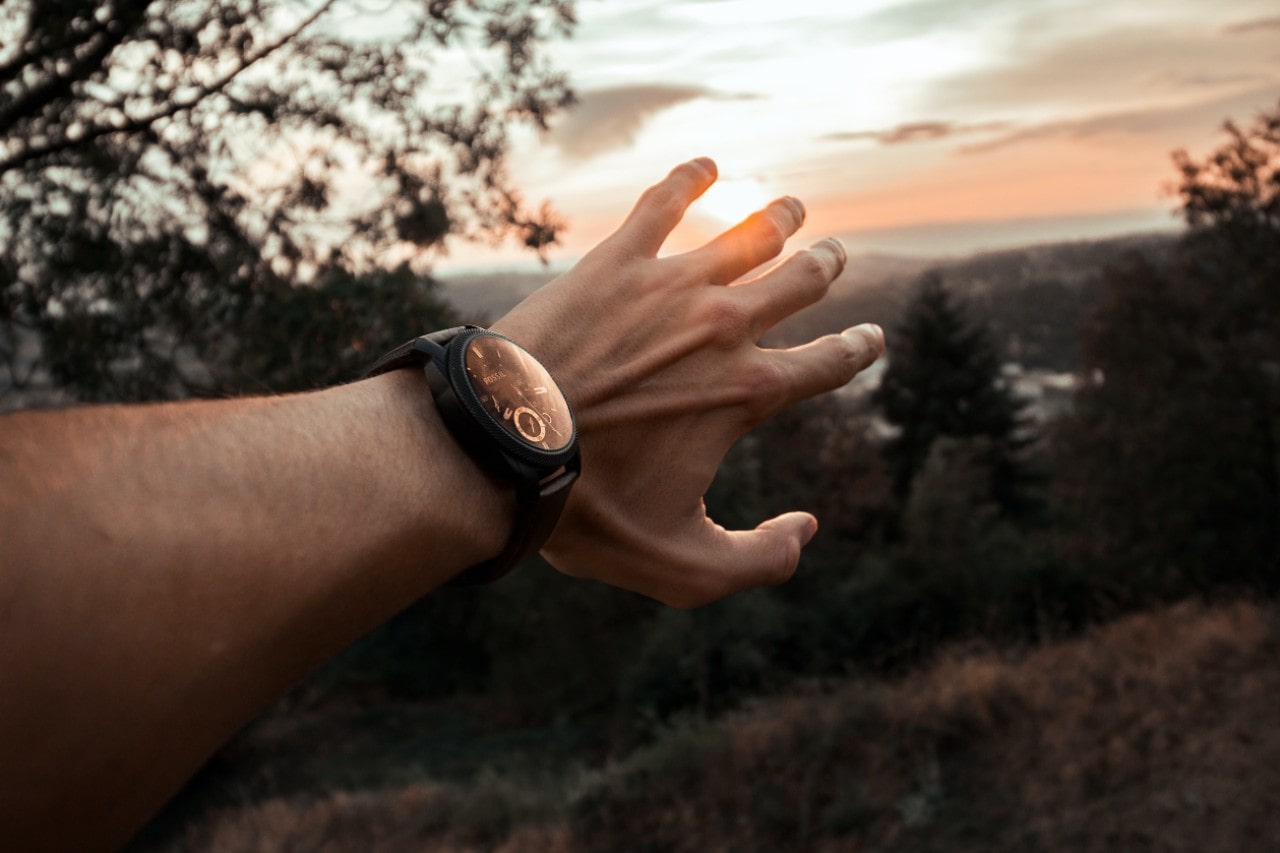 An outstretched arm with a luxury watch on during a sunset hike