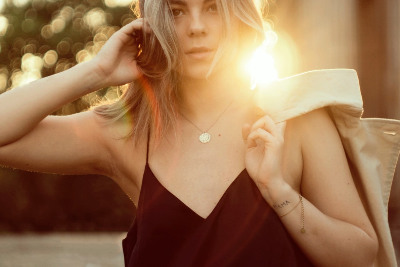 Woman with her jacket over her shoulder, wearing a gold pendant necklace