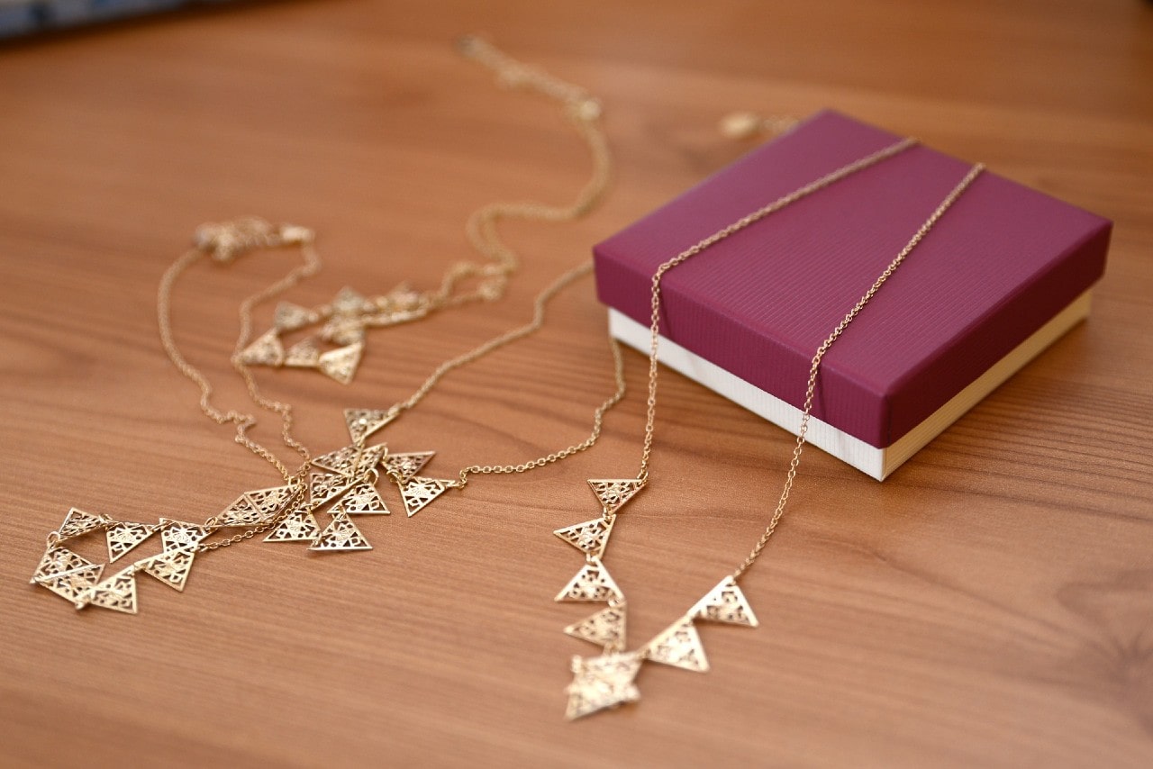 A necklace and a jewelry gift box sitting on a wooden table