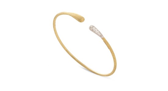 A yellow gold cuff bracelet features a diamond accent