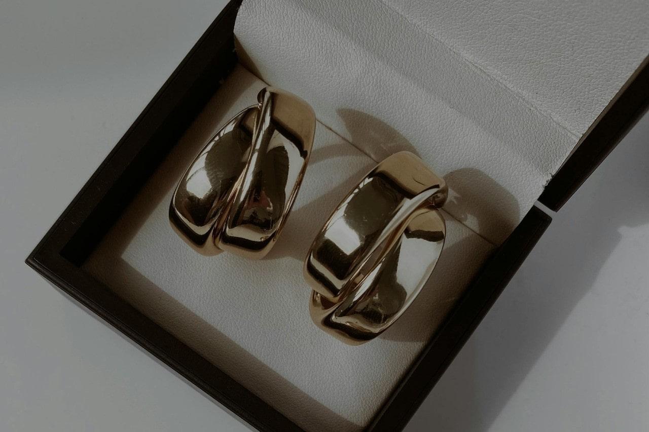 A pair of yellow gold huggie earrings in a black jewelry gift box.