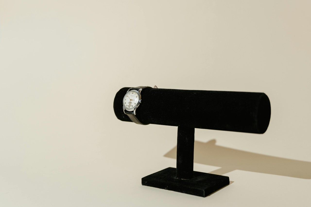 a black watch stand with a classic dress watch on its end