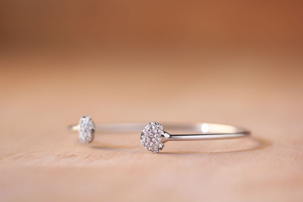 a white gold cuff bracelet featuring two heart motifs dotted with diamonds