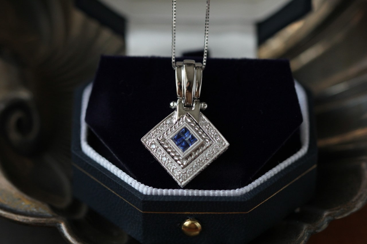a white gold pendant necklace set with sapphires in a luxurious jewelry box