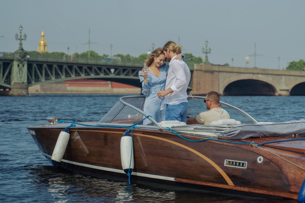 A couple celebrating in a vintage wooden speedboat after their proposal on the river as they explore Florida canals and their love.