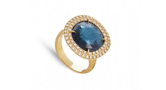 a yellow gold halo ring featuring an oval cut London blue topaz center stone