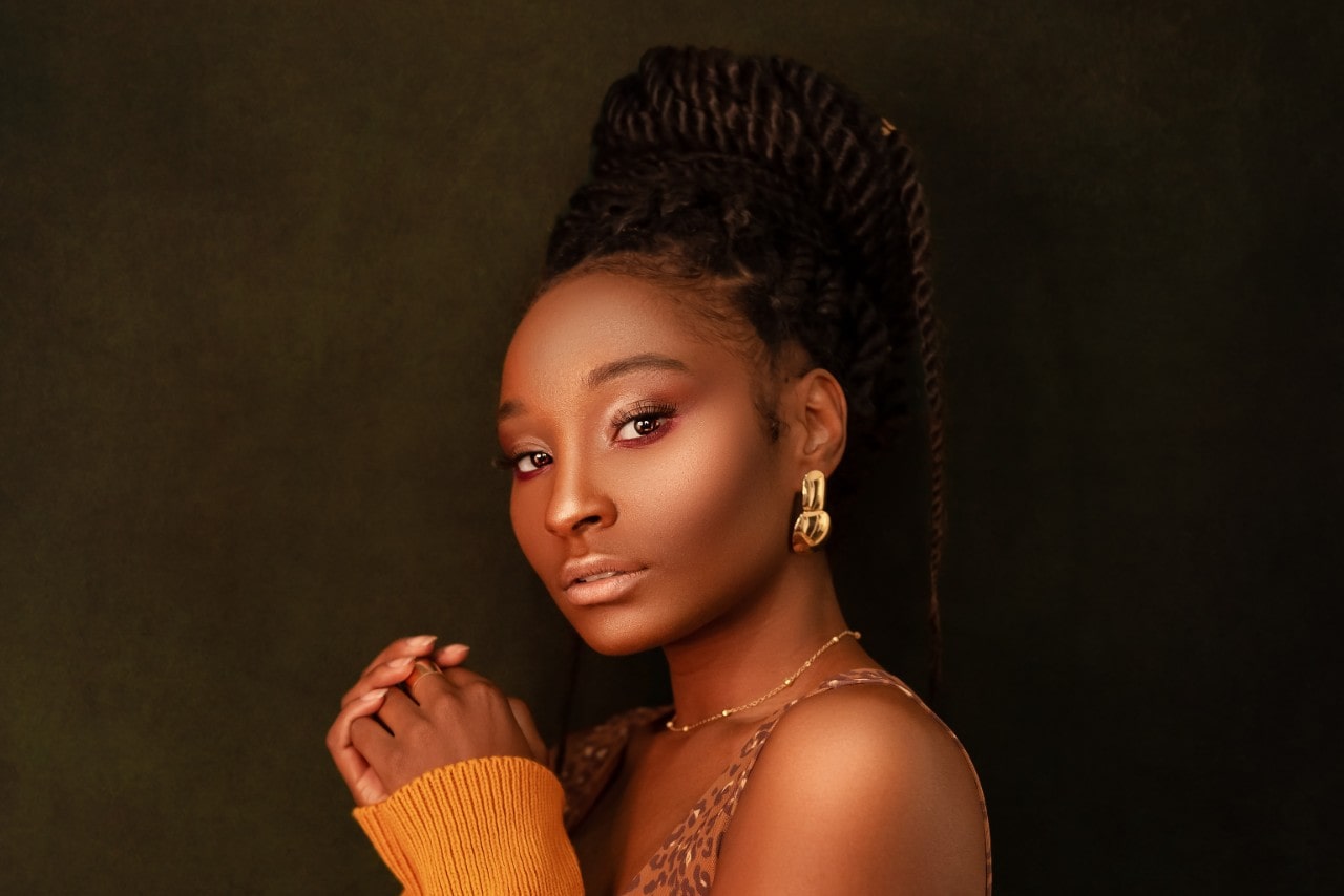 a woman with an elaborate updo wearing bold gold earrings and jewelry