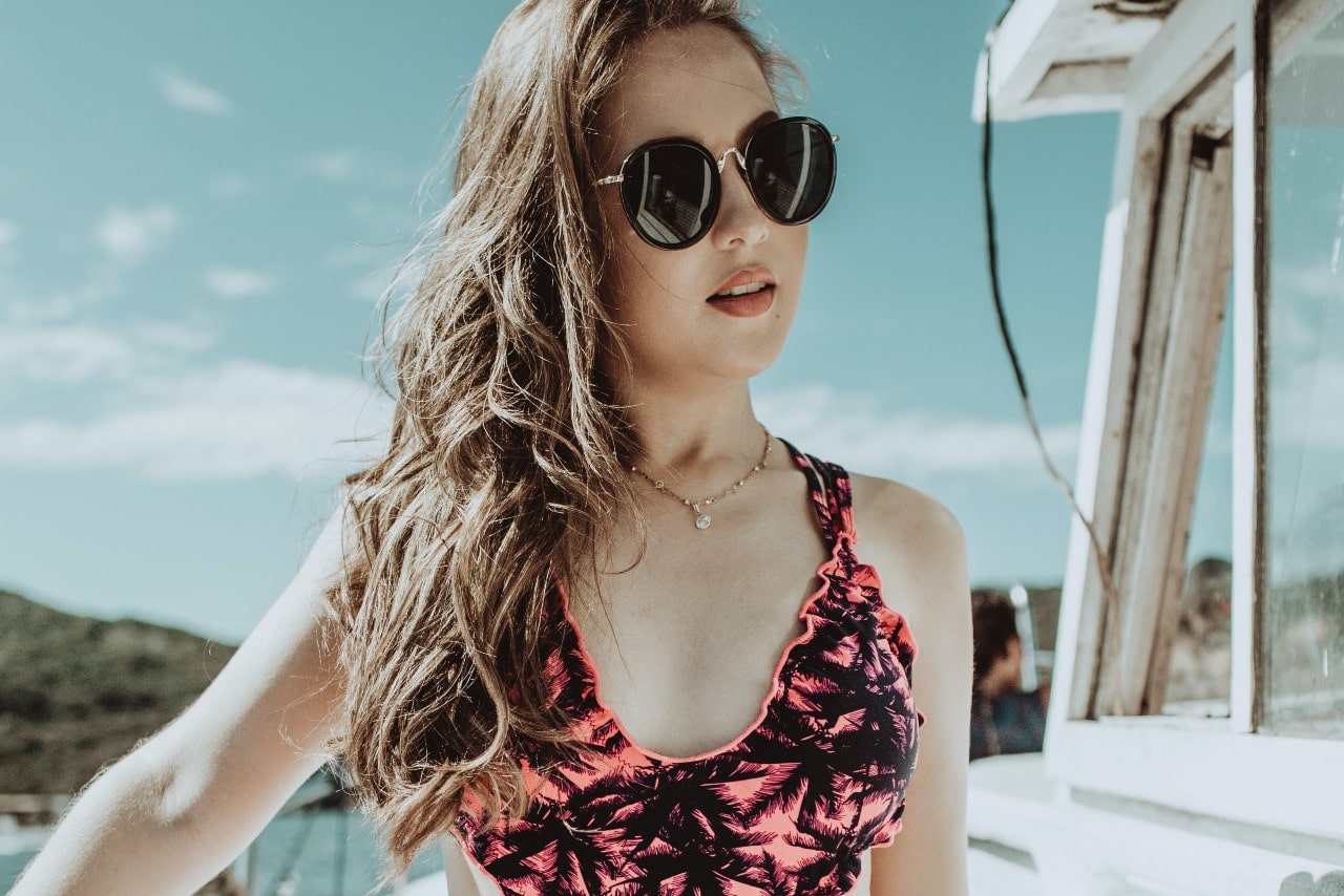 a woman standing on a boat wearing a gold chain necklace and a swimsuit