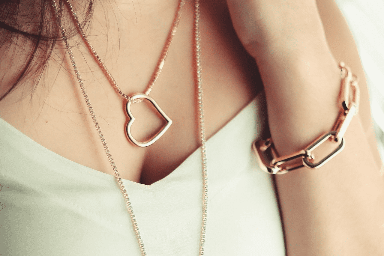 a lady wearing a gold bracelet and layered necklaces