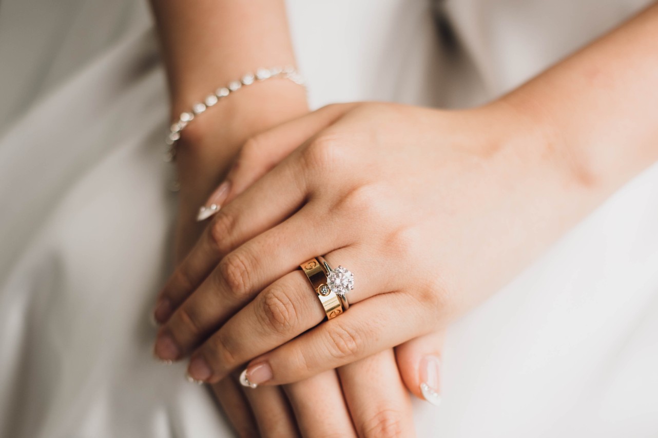 a bride with her hands stacked–wearing a yellow gold wedding band and an engagement ring