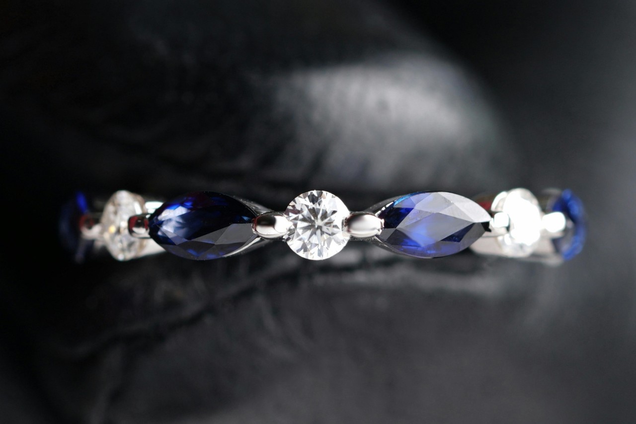 close up image of a silver toned wedding band with sapphires and diamonds