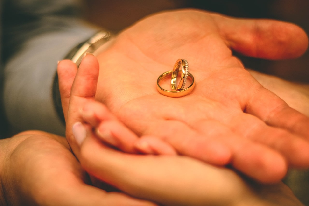 Man holding two wedding bands in his palm.