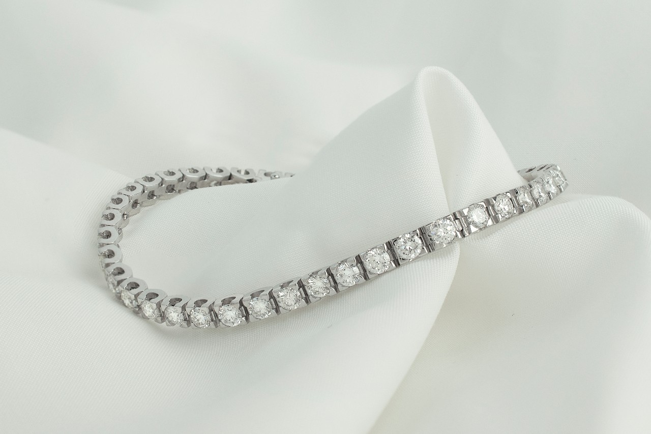 a white gold diamond line bracelet sitting on a piece of white fabric