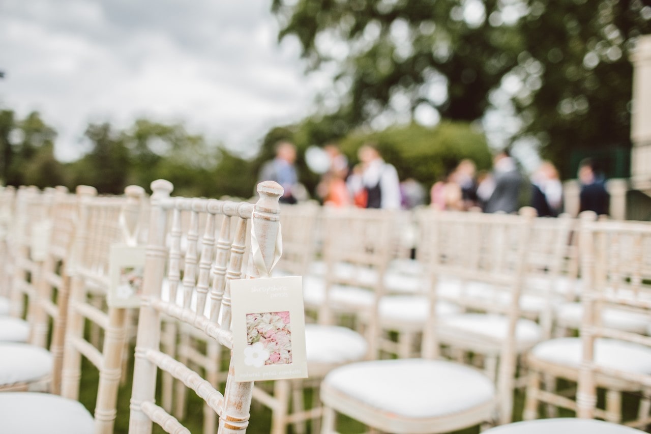 rows of white chairs set up outdoors for a wedding ceremony