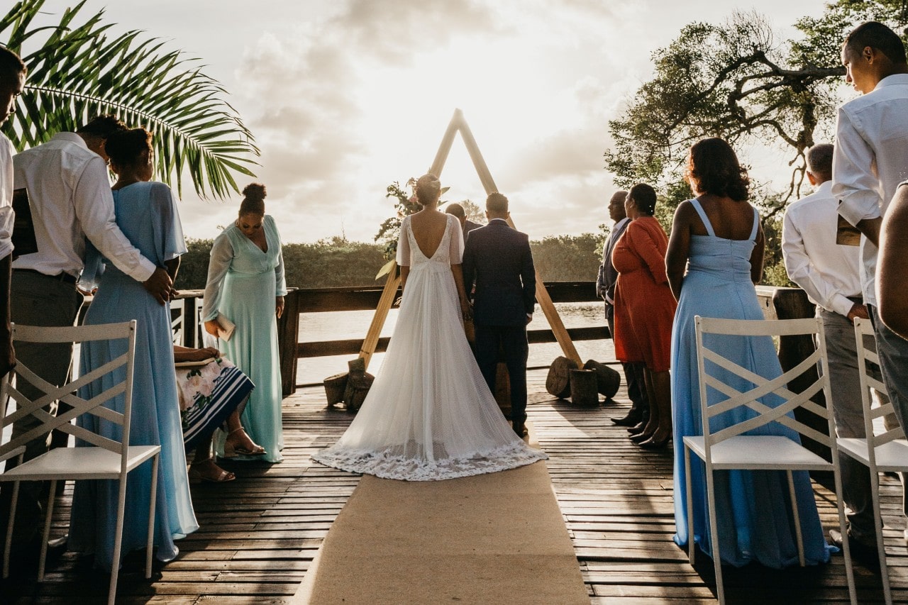 a bride and groom standing at the end of an isle outdoors