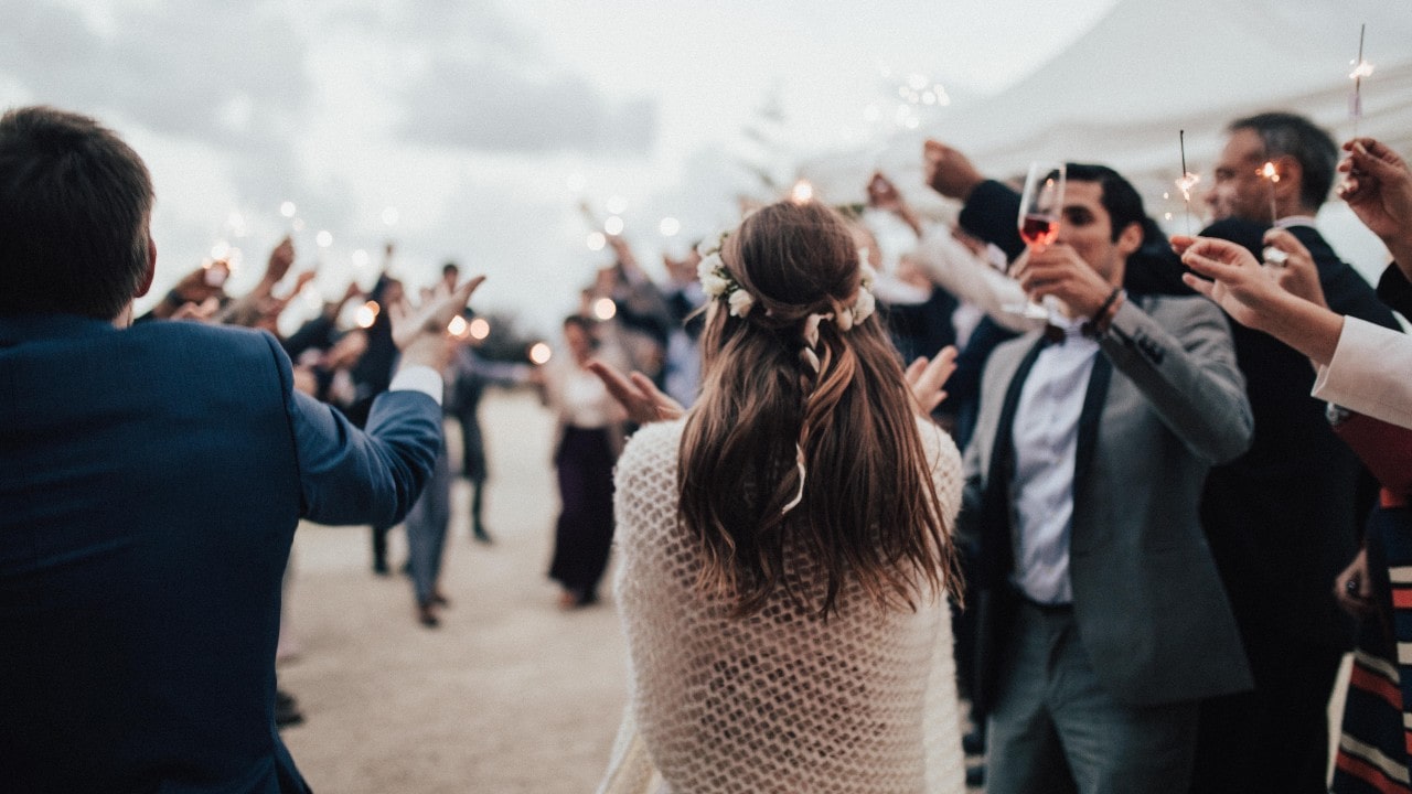 wedding guests holding up sparklers as the bride looks surprised