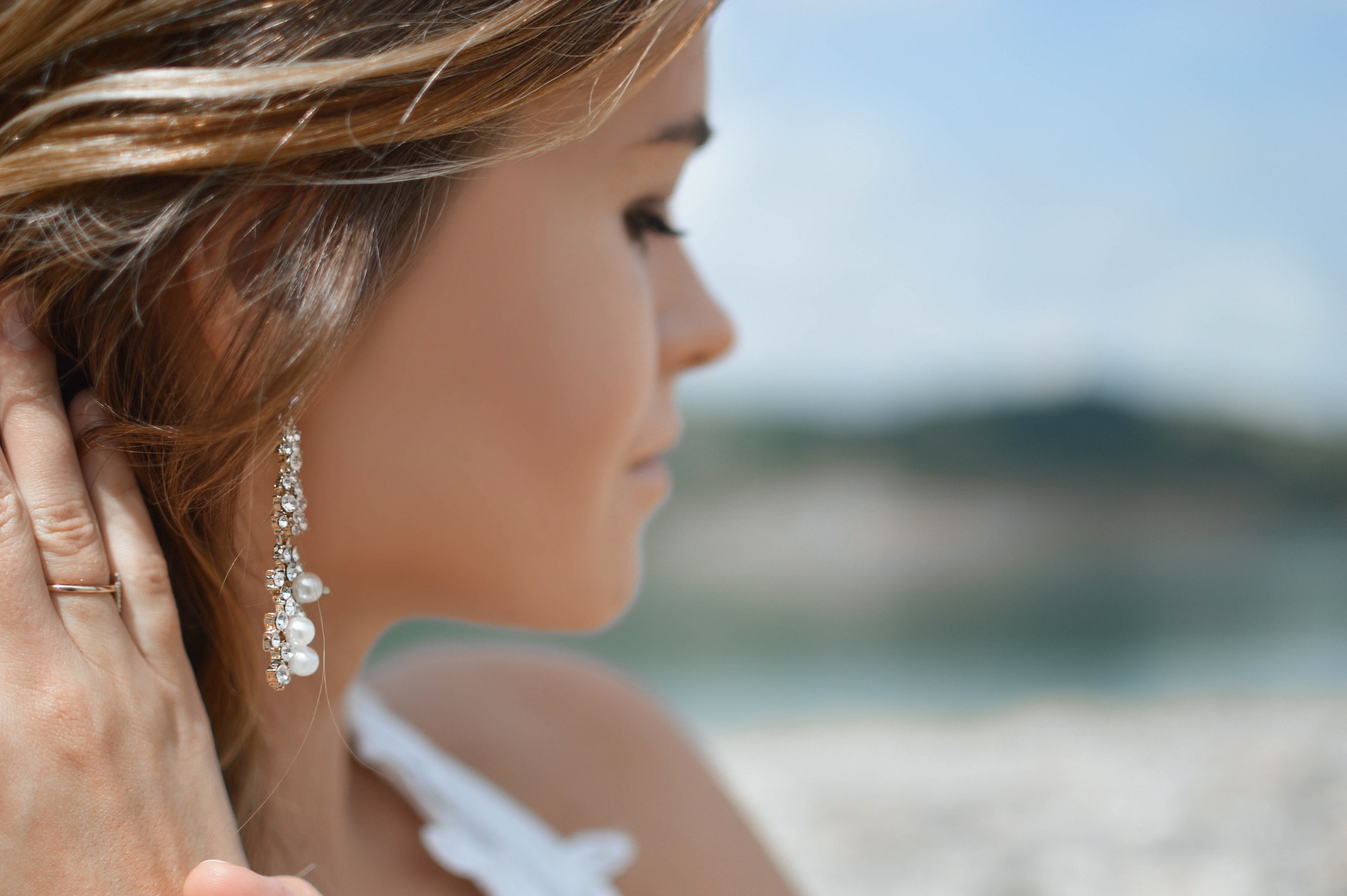 a woman looking away from the camera and revealing a pair of pearl and diamond earrings