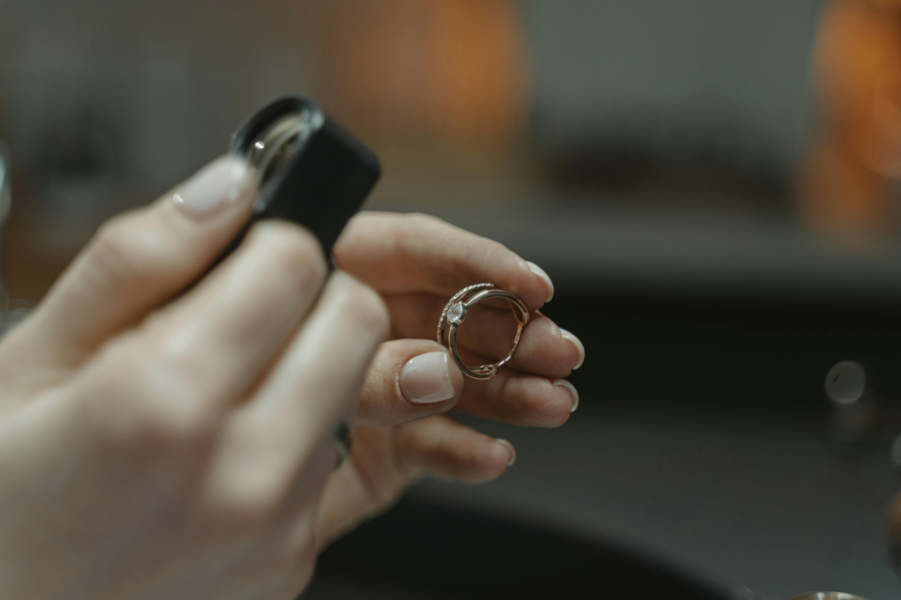 A close-up of a jeweler’s hand as they inspect an engagement ring through a loupe.