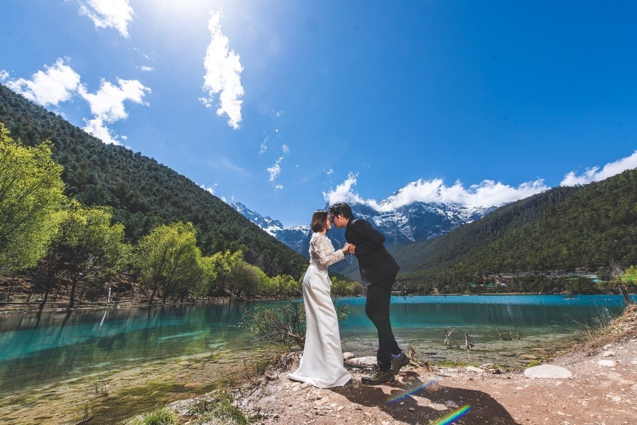 a happy couple embracing outside near water and mountains
