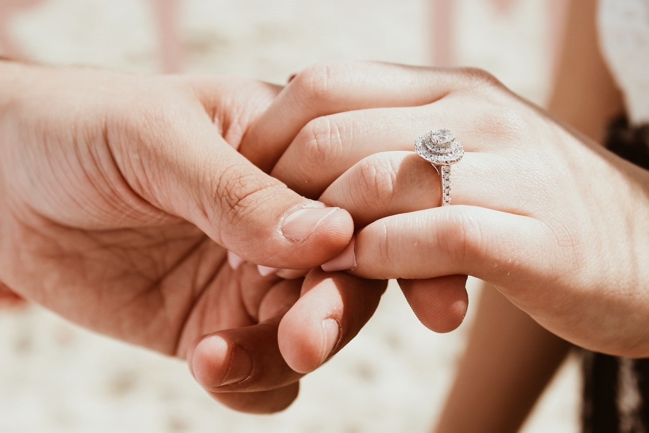 man holding a woman’s hand wearing an engagement ring