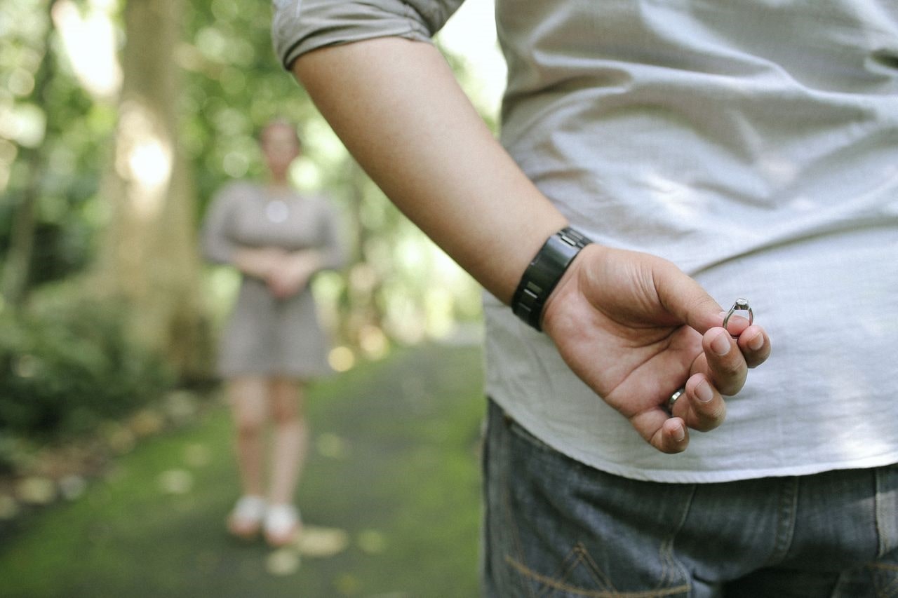 man holding a ring behind his back preparing to propose