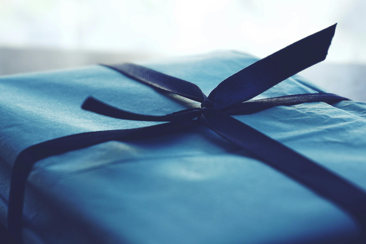 A close-up of a simple blue gift box wrapped with a blue ribbon.
