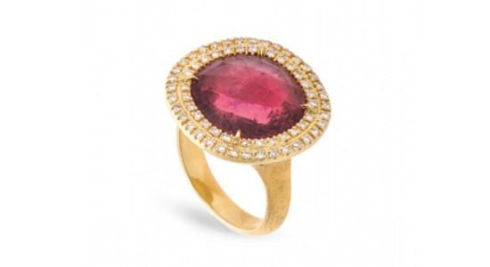 a yellow gold cocktail ring featuring a halo set, red gemstone