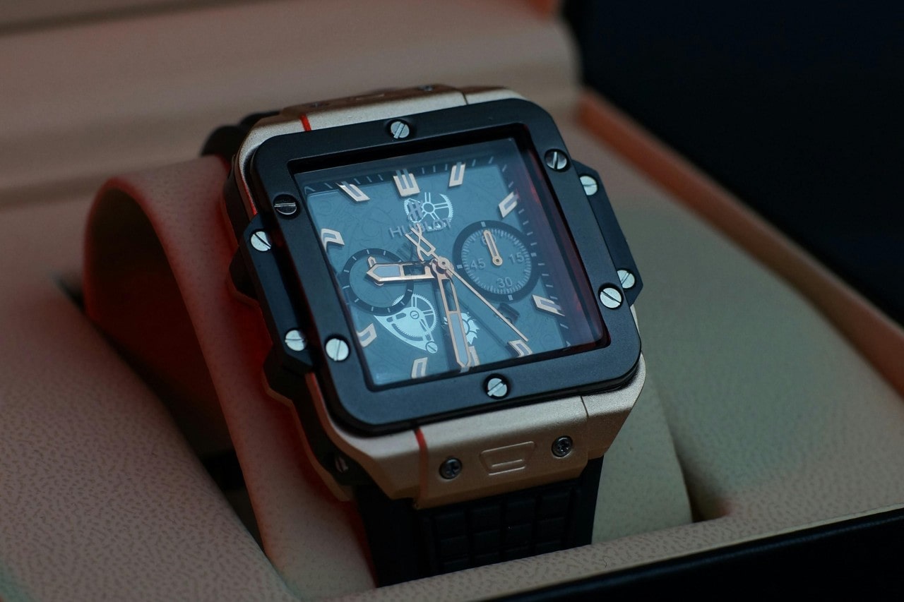 A close-up of a sporty Hublot watch with a square case displayed in-box.