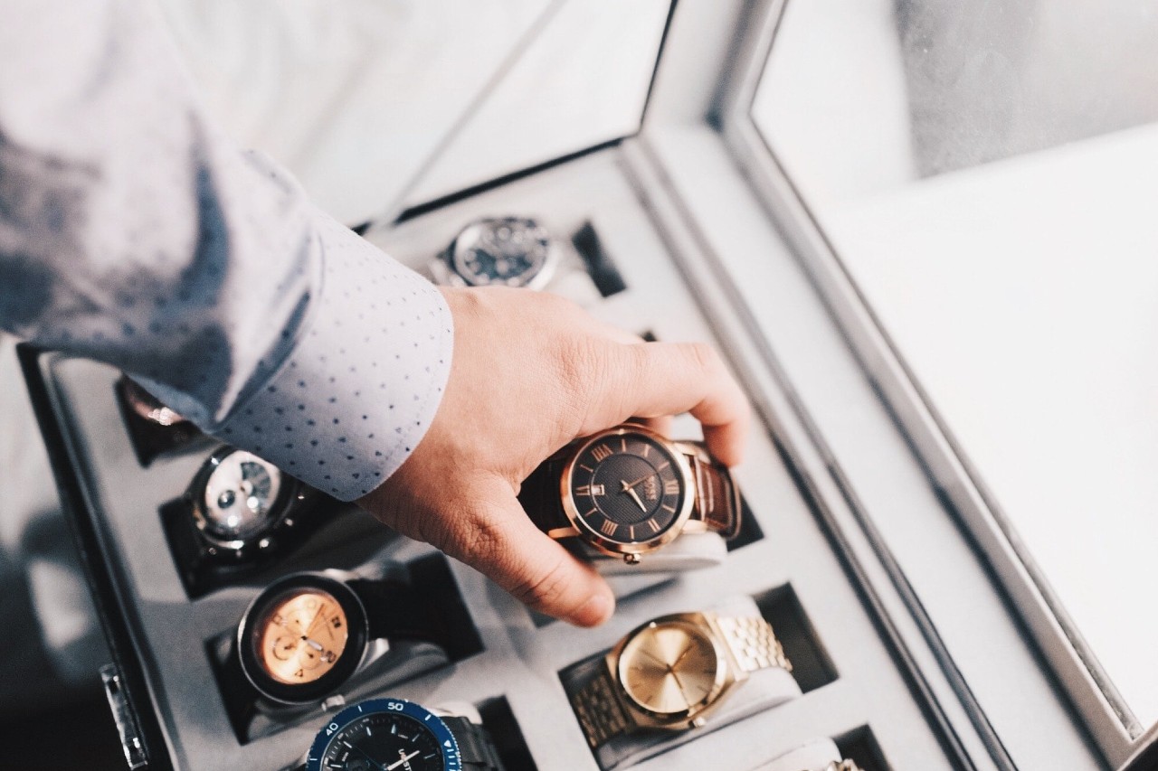 A man selects a dress watch from his watch collection.