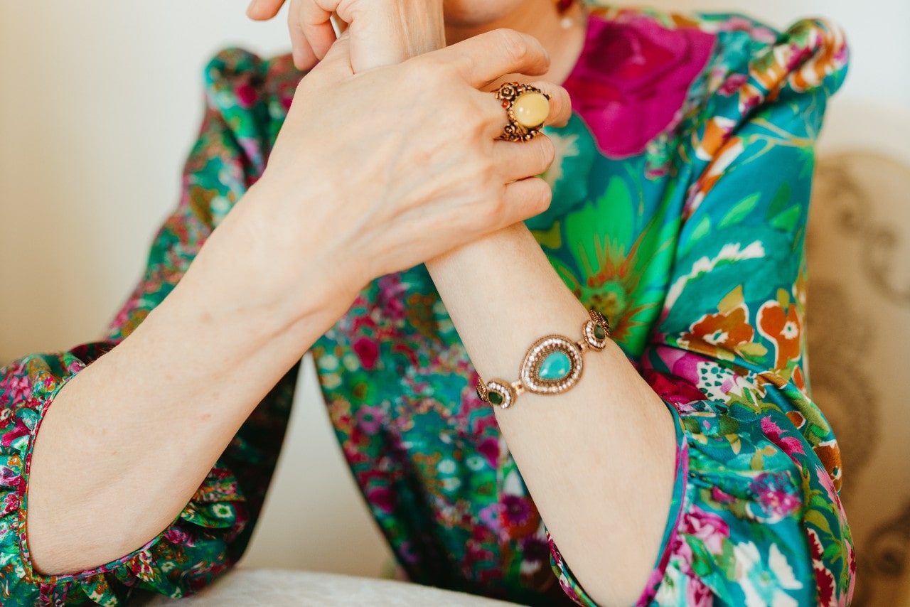 a woman in a colorful blouse wearing bold gemstone jewelry