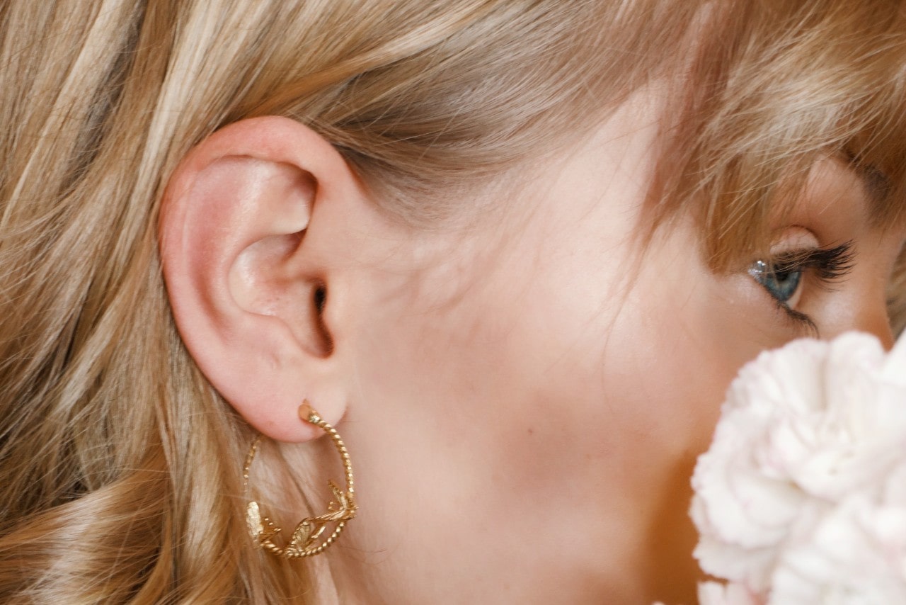 a woman looking away from the camera and wearing a textural gold hoop earring