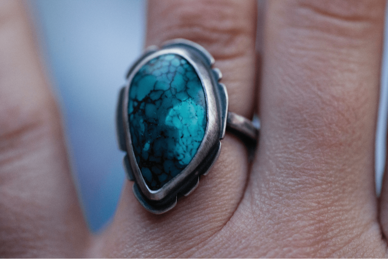 close up image of a person’s finger donning a silver and turquoise ring