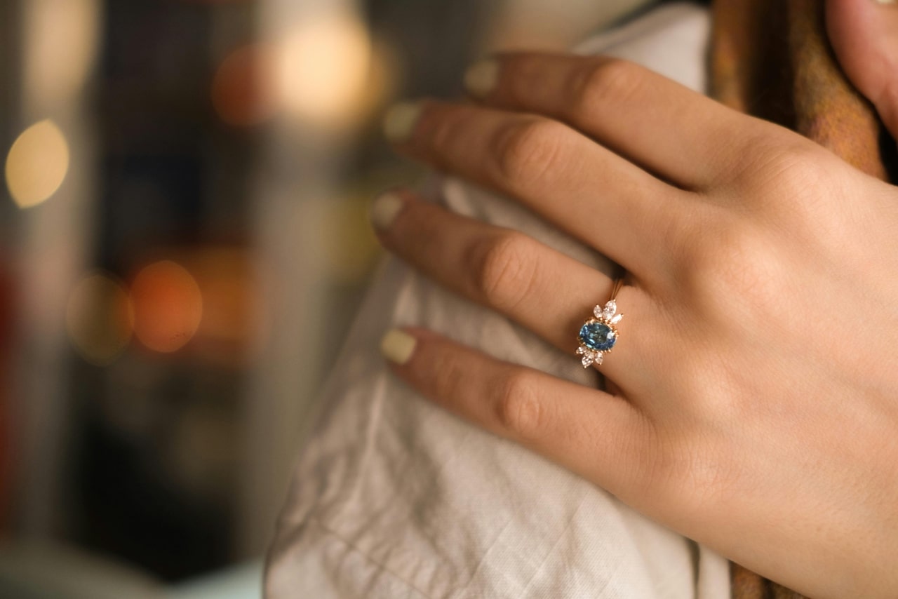 A woman's hand adorned with a yellow gold vintage-inspired sapphire and diamond ring A woman's hand adorned with a yellow gold vintage-inspired sapphire and diamond ring