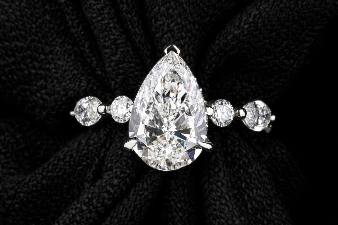 white gold engagement ring with pear shape center stone and round cut side stones white gold engagement ring with pear shape center stone and round cut side stones