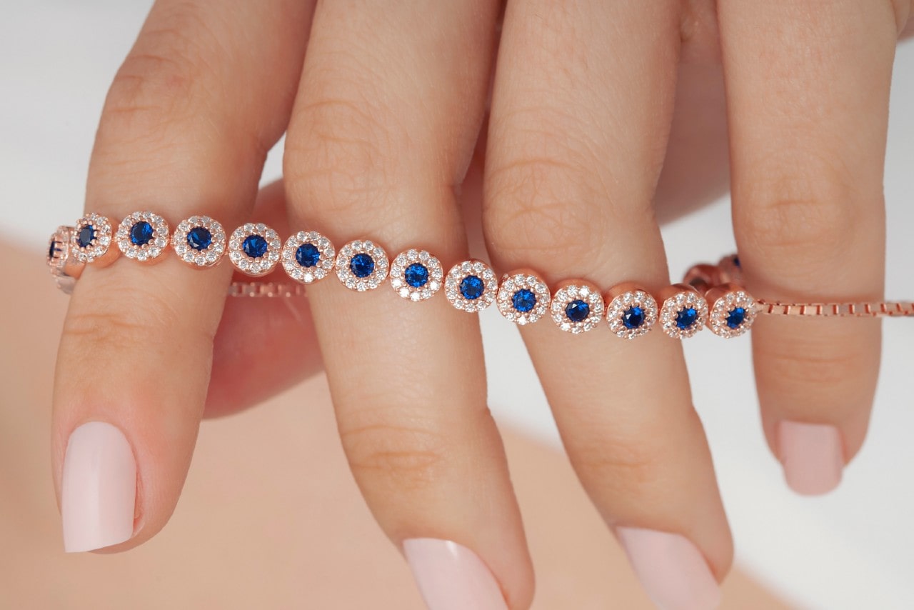 A woman holding a sapphire and diamond rose gold bracelet